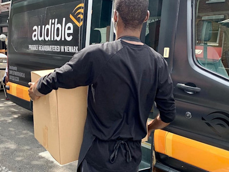 An employee from a NWK participating restaurant carries a box full of meals to the shuttle.