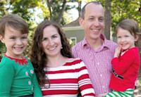 A young boy and girl are being held by their mother and father, posing for a photo. All are dressed in festive holiday clothing. This is the Wenks family.