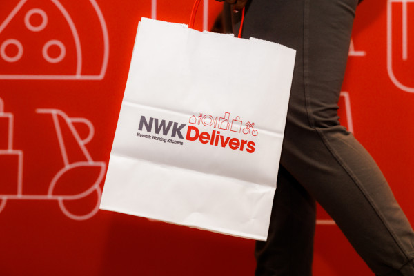 White NWK Delivers bag with logo and food-related icons.