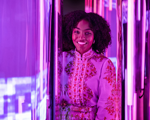 Yara Shahidi stands in a brightly lit purple room.