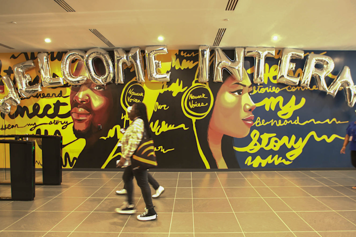 Students walk across the lobby with balloons in the background that say "Welcome Interns"