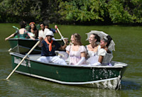 A photo of several people wearing Edwardian-era and fantasy clothing on rowboats in New York's Central Park.