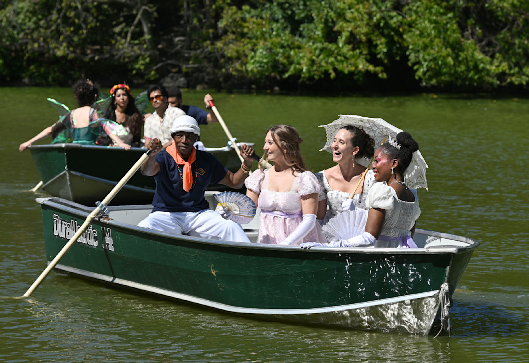 A photo of several people wearing Edwardian-era and fantasy clothing on rowboats in New York's Central Park.