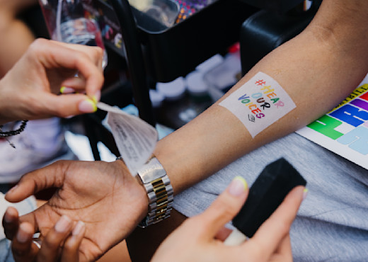 A temporary tattoo saying #HearOurVoices is applied to someone's arm.