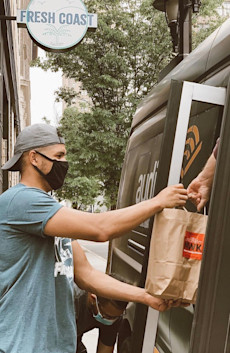 An employee from Fresh Coast hands shuttle driver a NWK meal.