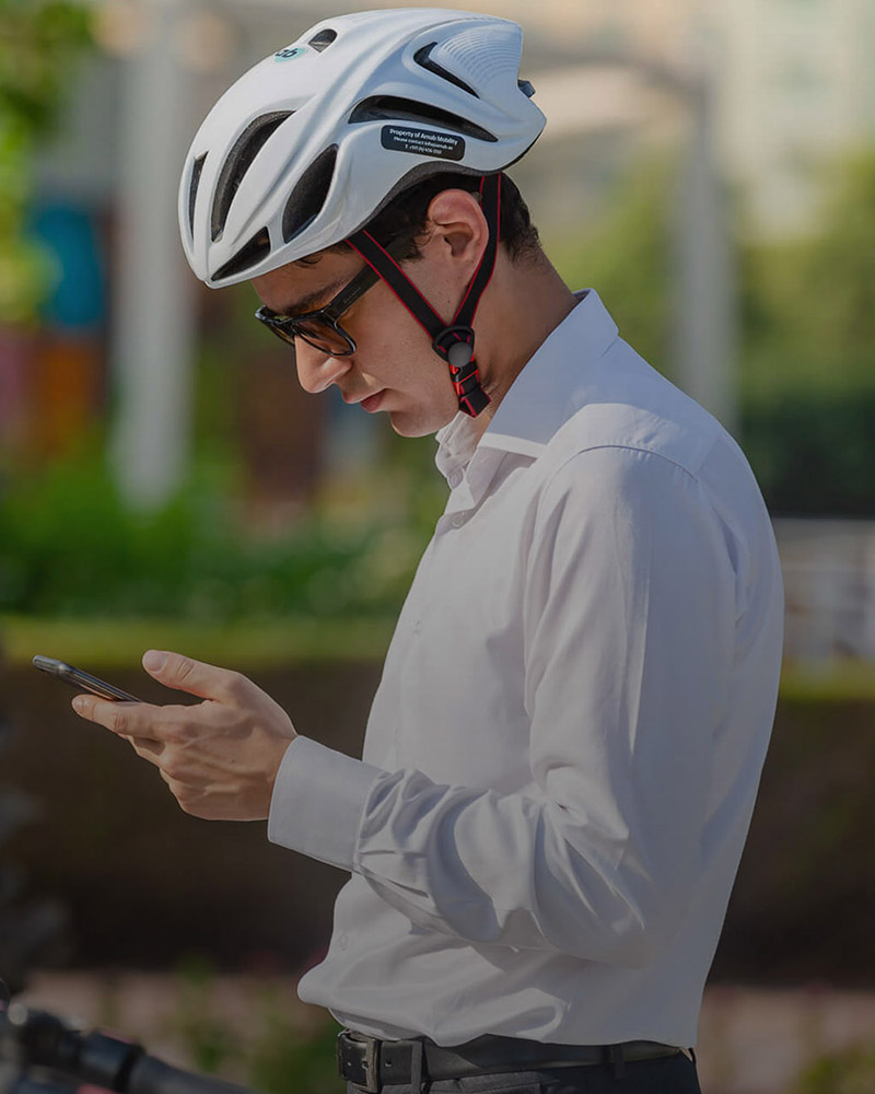 Customers hero image for Arnab featuring a caucasian man standing with a helmet looking down on his mobile phone.