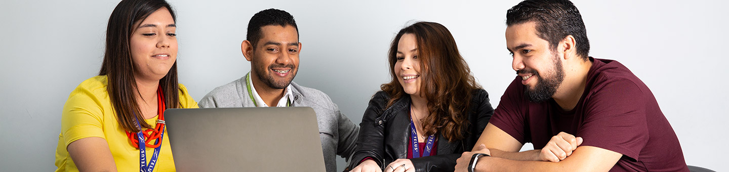 Four employees looking at a laptop