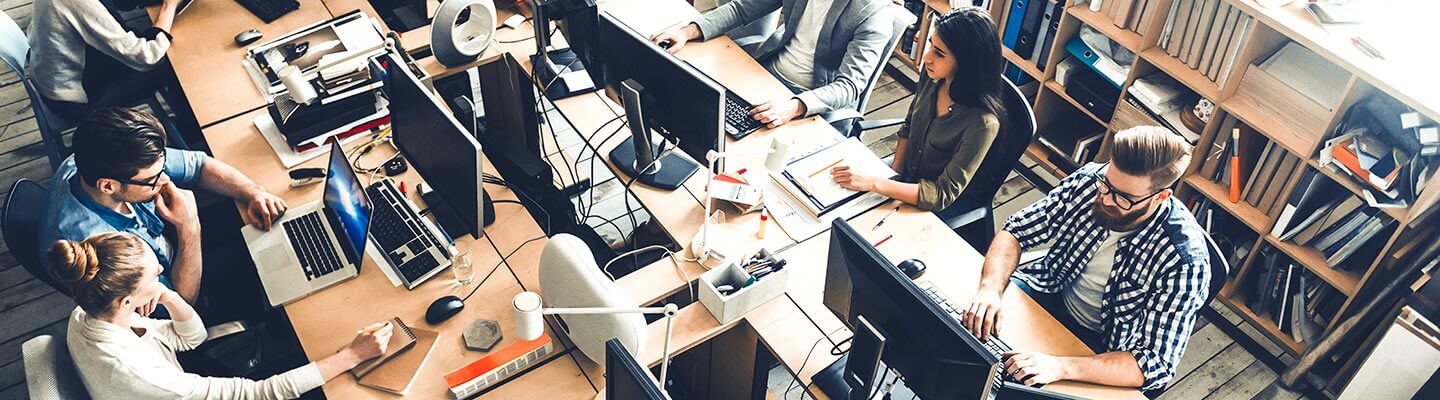 A room of people around a table on their computers and laptops