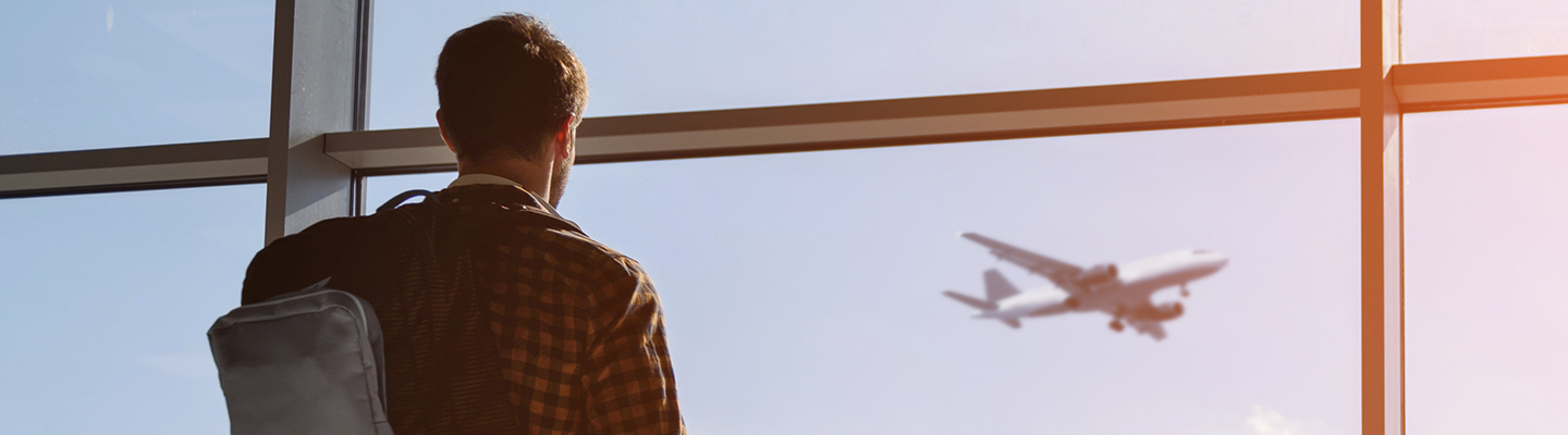 Man with backpack staring out window at airplane