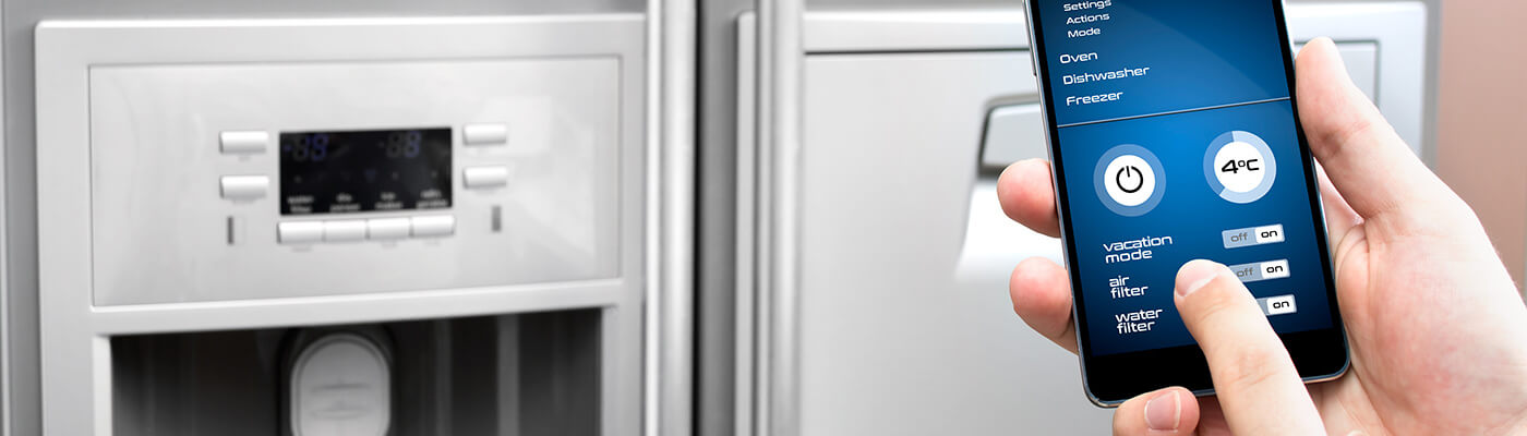 Person holding a mobile phone connected to a smart fridge