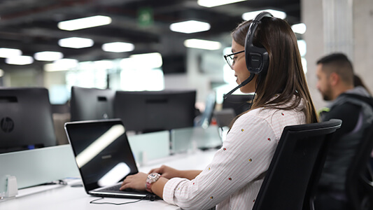 Woman on a headset working on a laptop