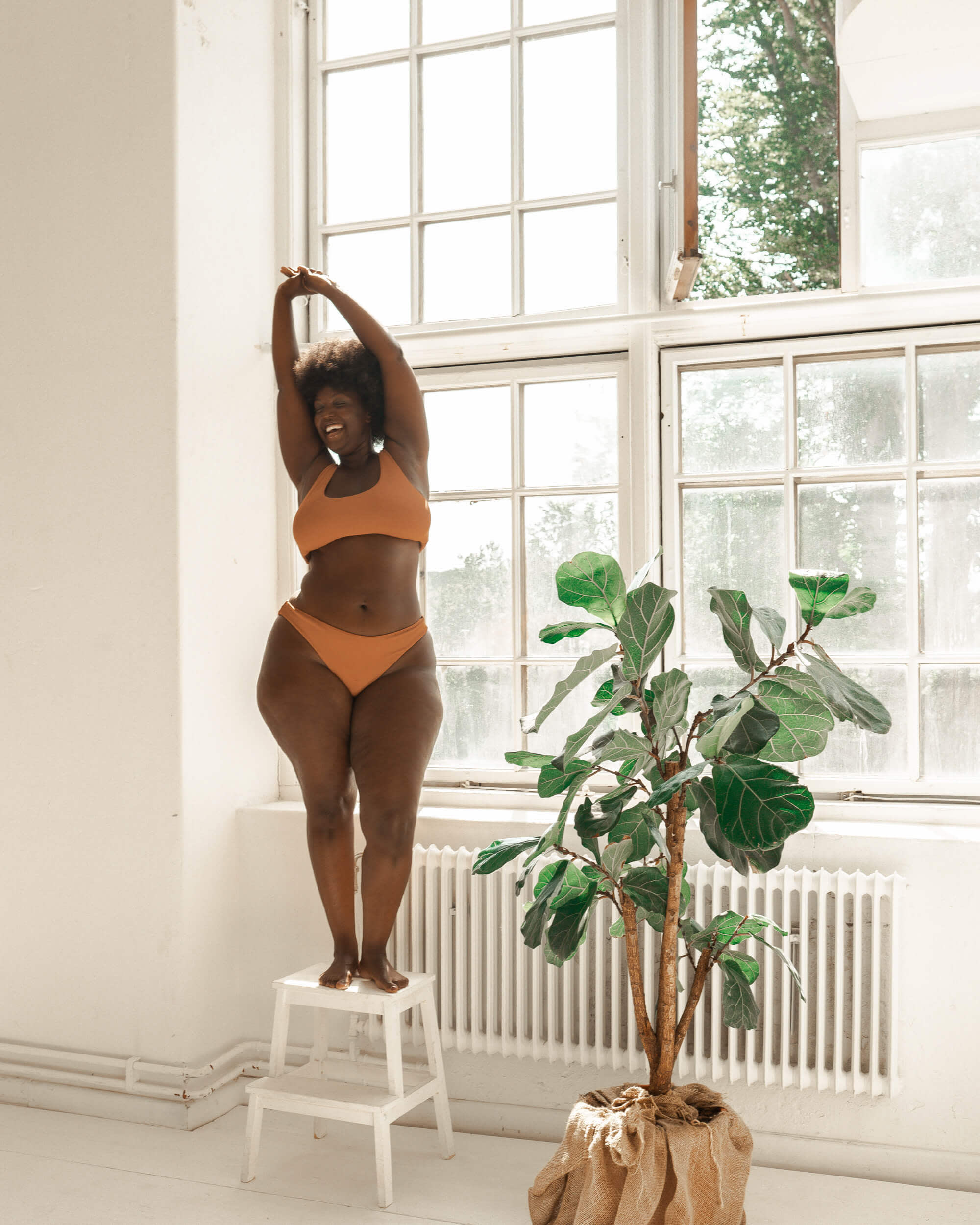 En person i ett orange plagg som står på en pall framför ett fönster