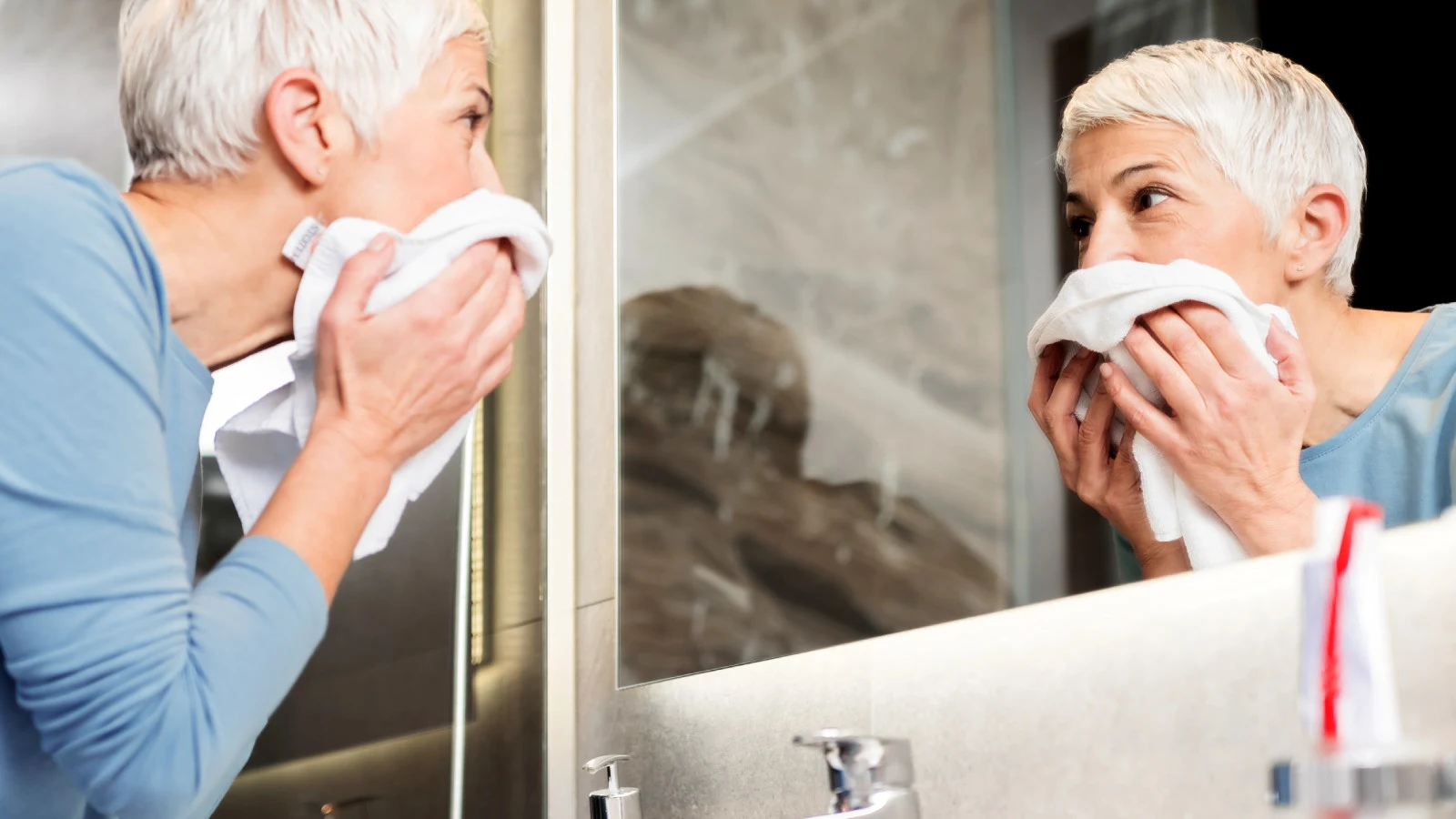 Kvinna som torkar hennes ansikte med en handduk