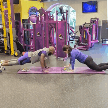 Man and woman working out in Planet Fitness gym doing push-ups with shoulder taps