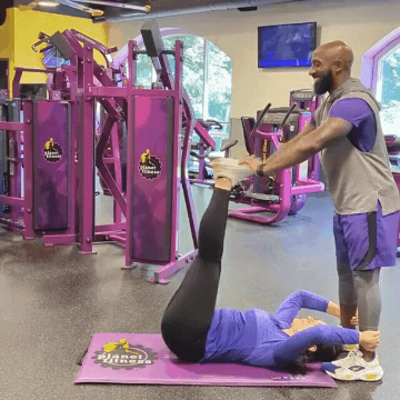 Man and woman working out in Planet Fitness gym doing leg push-downs