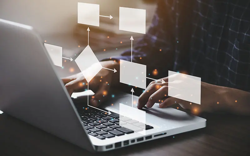 Person typing on laptop with flowchart graphic overlayed