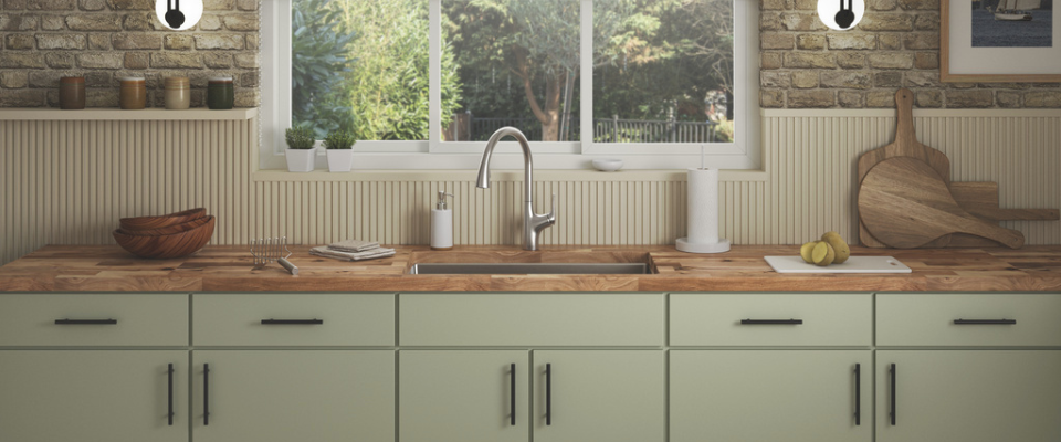 Dapur dengan kabinet hijau, countertop kayu, dan kran krom