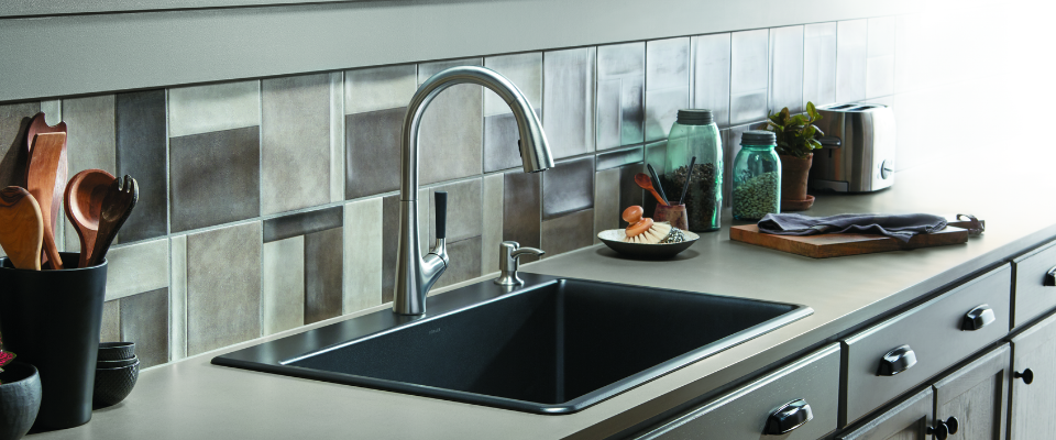 Wastafel dapur gelap dengan kran melengkung dan peralatan dapur di atas meja