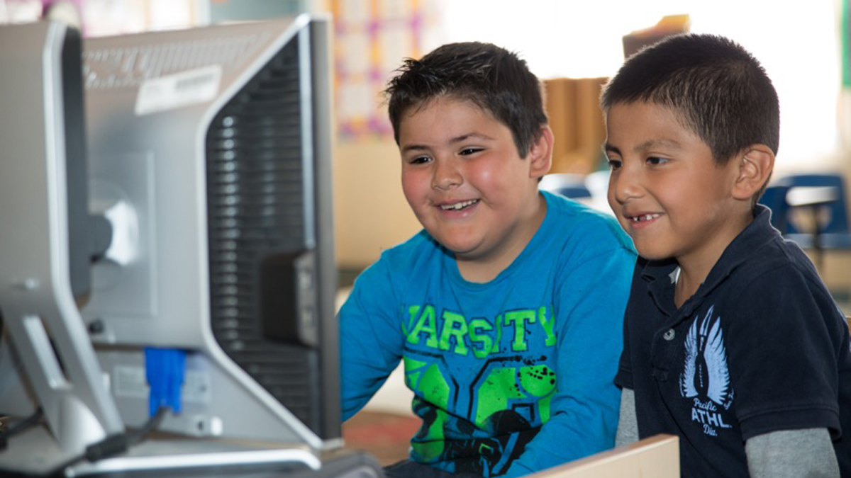 Two kids sharing a computer monitor