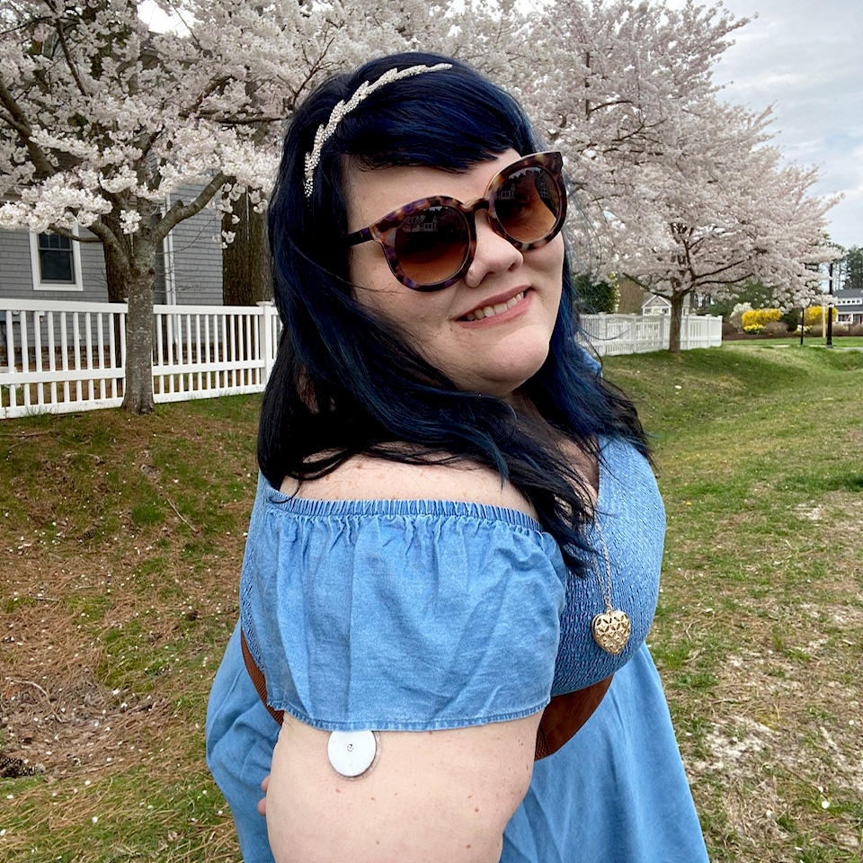 Photo of Liz Davis, who has Type 2 diabetes, wearing sunglasses outdoors and showing her arm, which has a continuous glucose monitor on it.