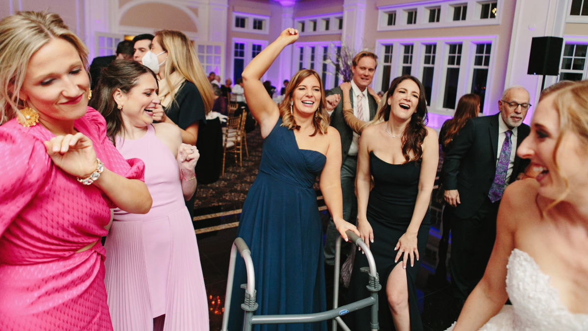 Brooke Eby is pictured with her walker on the dance floor of a wedding, surrounded by friends.