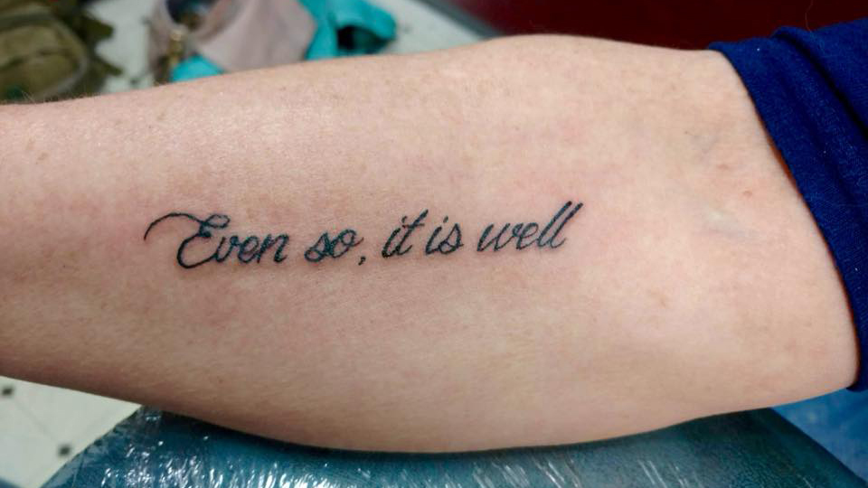 Close-up of Vickie Hadge’s forearm shows a tattoo that reads, “Even so, it is well.”
