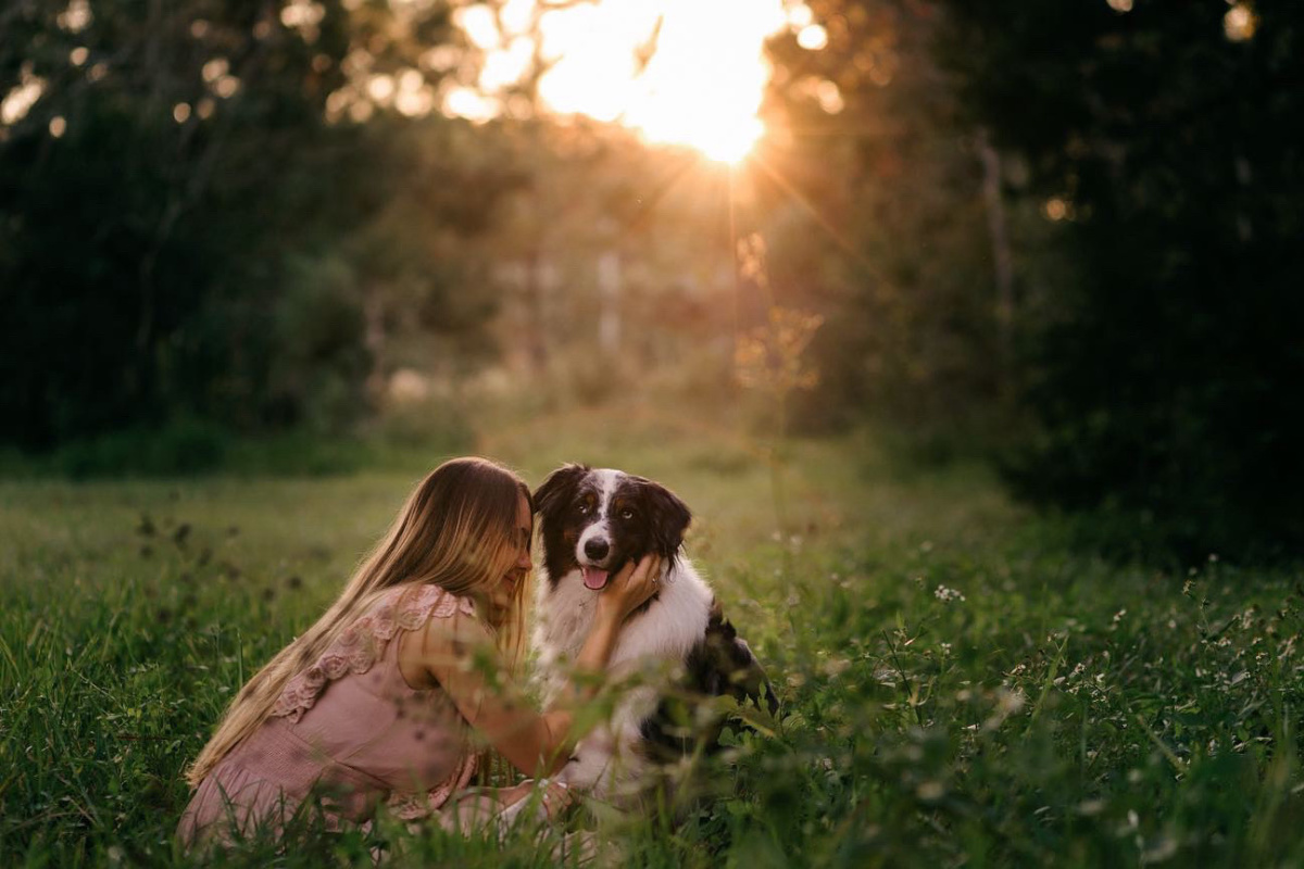 Jaime Simpson is pictured in a field embracing her service dog, Echo, an Australian shepherd.