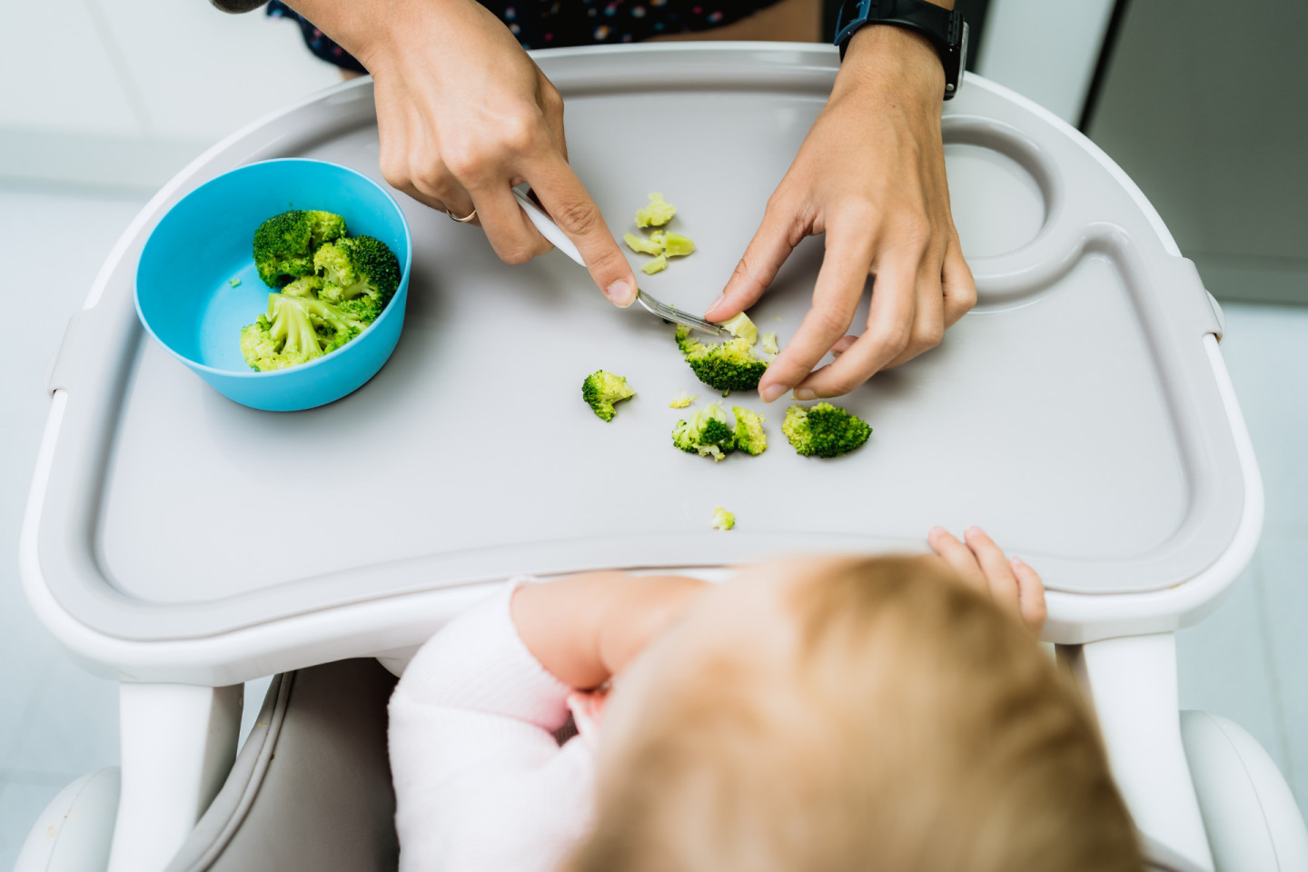 Mom serves finger foods for baby: Chopping up broccoli for baby led weaning.
