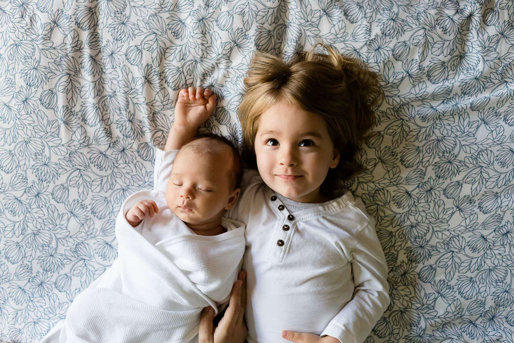 Two children laying next to one another on a bed