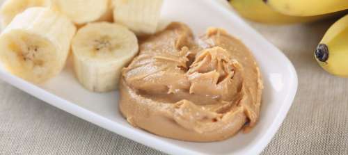 Peanut butter on bread with banana slices on a plate