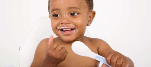 A baby eating from a spoon.