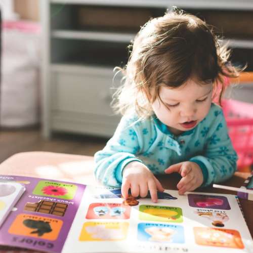 A toddler looking at a book.