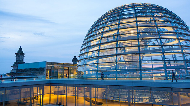 Die gläserne Kuppel des Berliner Reichstages wird in der Dunkelheit beleuchtet.