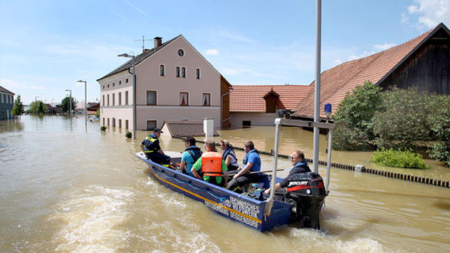 Helfer des Technischen Hilfswerks fahren mit dem Boot durch die überflutete Stadt