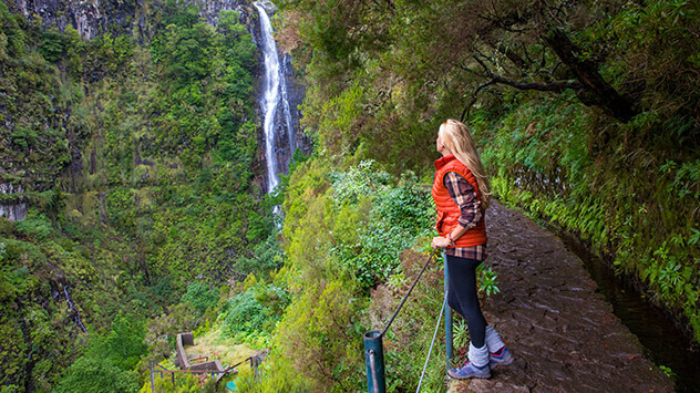 Frau schaut auf Wasserfall auf einer Wanderung an den Levadas 
