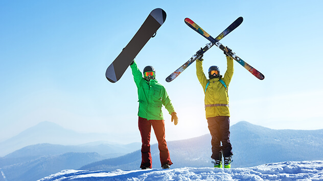 Skifahrer und Snowboarder auf einem Berggipfel