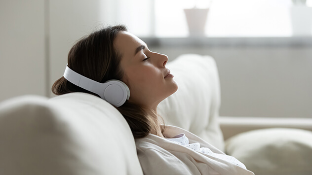 Frau entspannt mit Kopfhörern auf dem Sofa