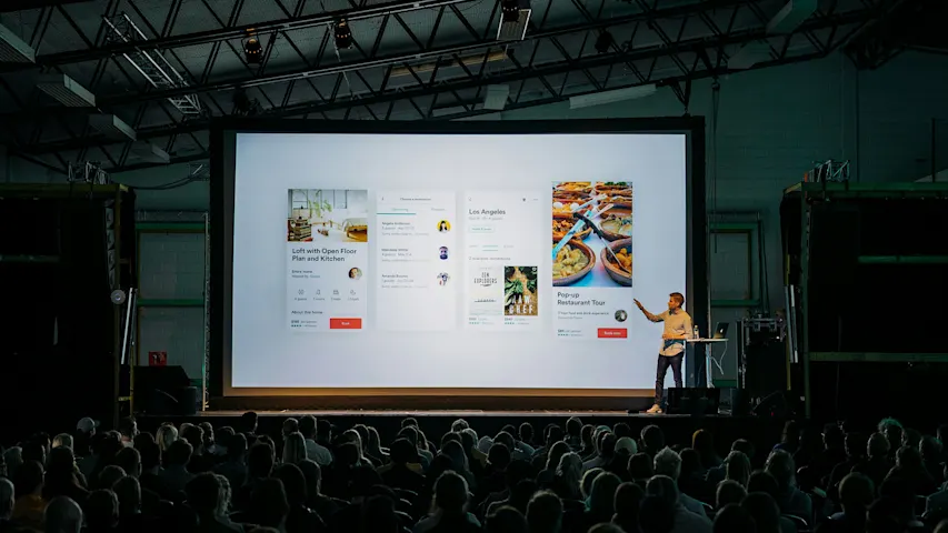 Image of a person giving a presentation on a stage in front of an audience