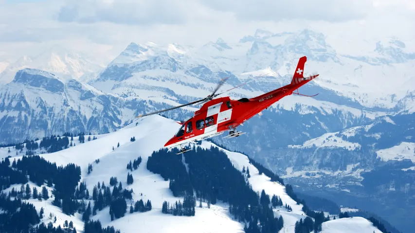 Photo of an emergency helicopter flying above snow-capped mountains