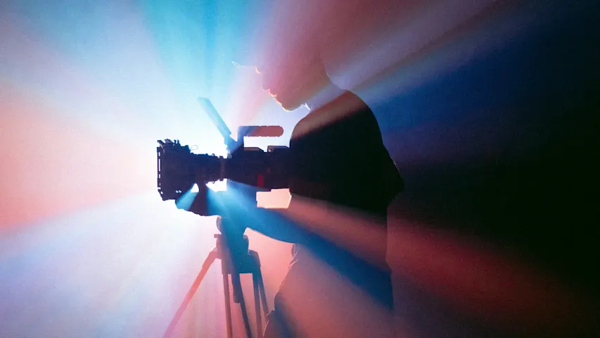 Abstract photo of someone filming with light rays shining from behind them