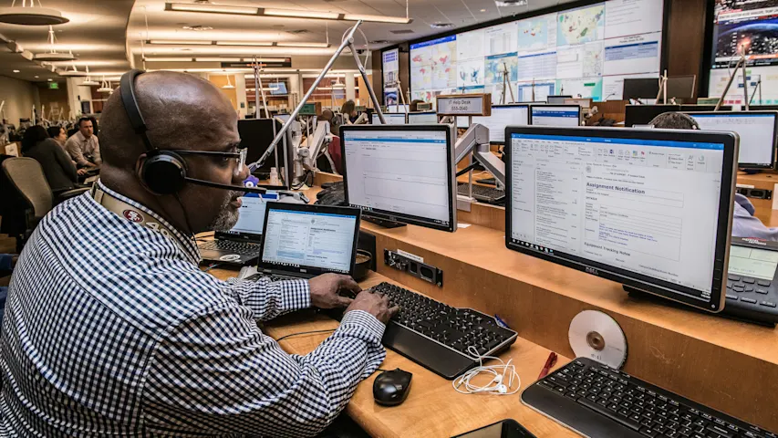 Image of a customer service agent working on multiple computer monitors