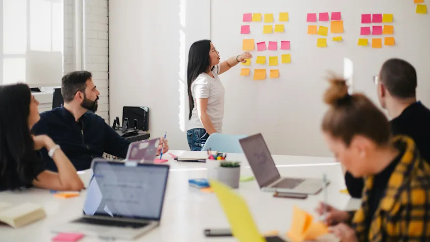 Photo of several people in brainstorming meeting using sticky notes