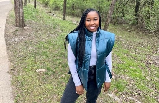 Jasmine Brown standing in front of a grassy slope healthy green forests 