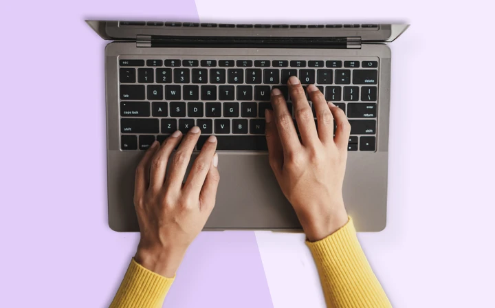 Overhead shot of hands typing on a laptop keyboard.