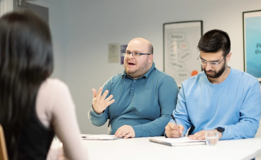 Two interviewers, one is asking a question while the other makes notes.