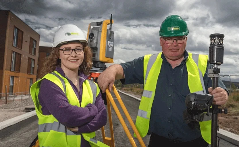 woman and man in high vis jackets and safety hats looking at camera
