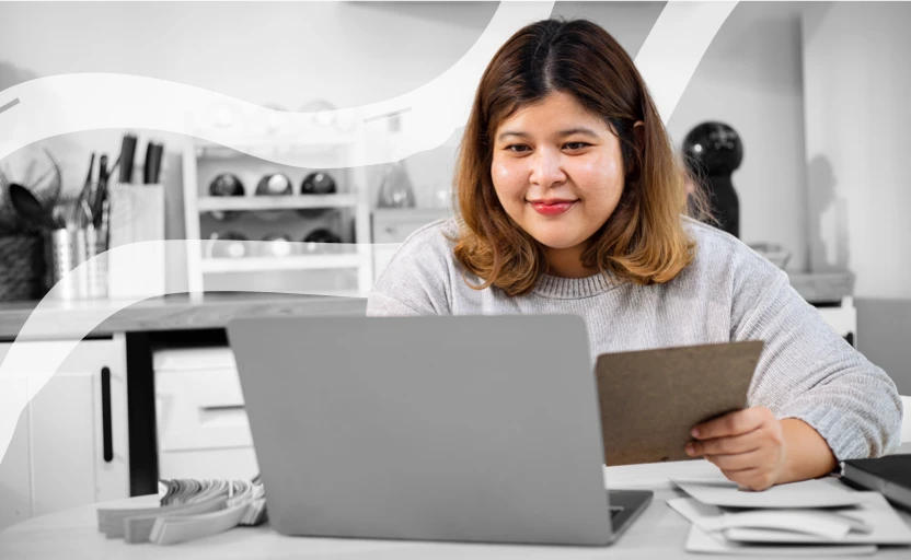 a girl sitting at a desk smiling in front of a laptop