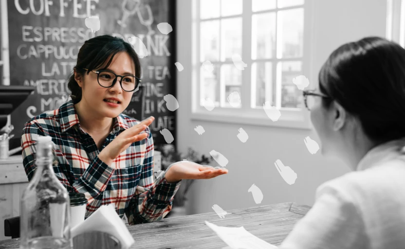 2 people in a job interview, 1 person is gesturing as they answer a question.