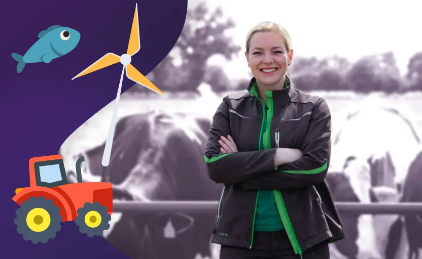 A smiling woman stands with her arms folded in front of a herd of cows.