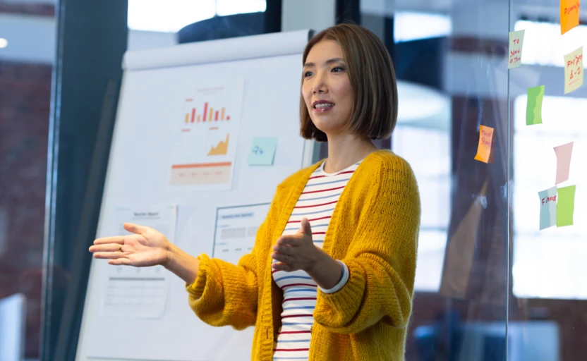 A person standing up, presenting to their work colleagues.